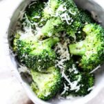 broccoli in a bowl with shaved parmesan cheese and pepper on top