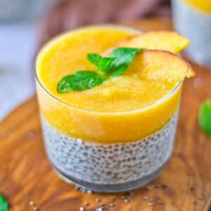 small jar of peach chia pudding with a mint sprig and sliced peaches on top