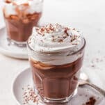 thick keto hot chocolate drink in a clear glass topped with whipped cream and chocolate shavings