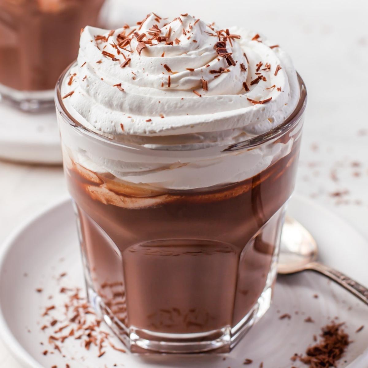 hot chocolate in a clear glass with whipped topping