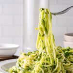 fork lifting a large amount of zucchini spirals from plate