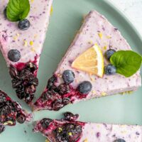 slice of blueberry cheesecake with a lemon wedge and garnish